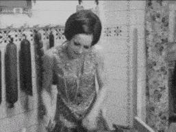 a woman is standing in front of a wall with sausages hanging from it