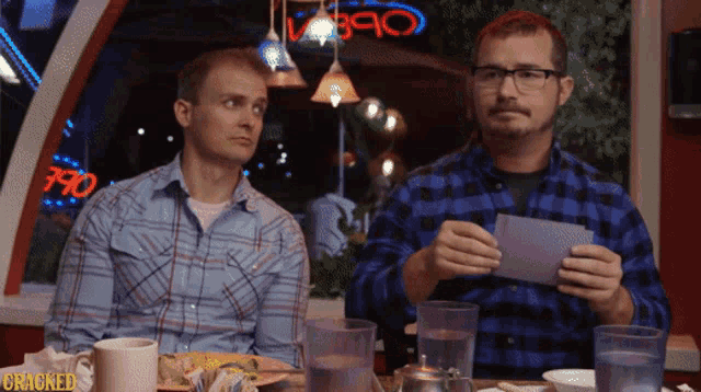 two men sitting at a table with a sign that says cracked on it