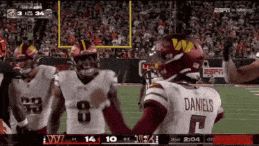 a football player wearing a daniels jersey is standing on the field with his teammates