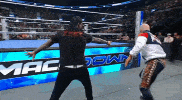 two men are wrestling in front of a sign that says macdown