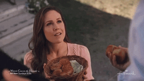 a woman is holding a basket of food in front of a sign that says when calls a heart