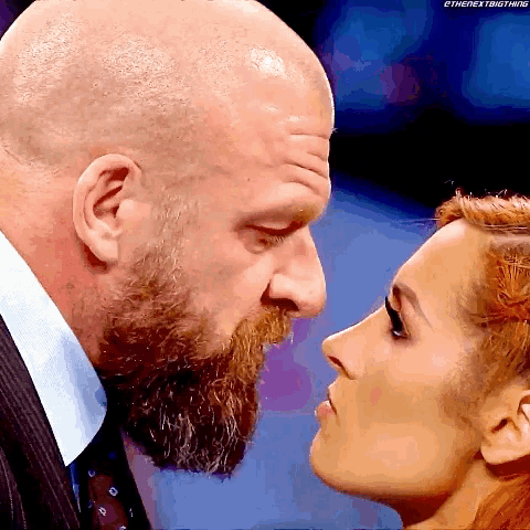 a bald man with a beard and a woman with red hair are looking into each other 's eyes ..