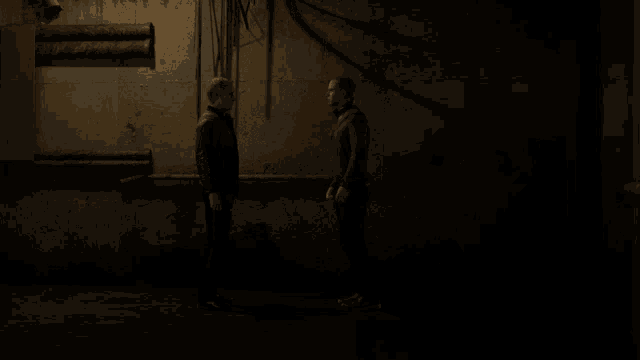 two people hugging in a dark room with pipes hanging from the walls