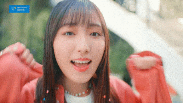 a girl is wearing a red jacket and a white shirt with a blue banner that says upfront working on it