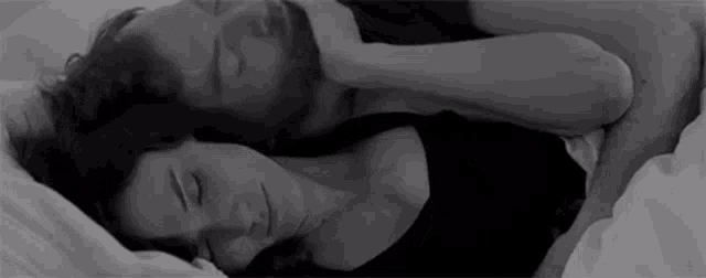 a man and a woman are sleeping next to each other in bed .