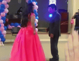 a man in a suit and a woman in a pink dress are dancing in front of balloons
