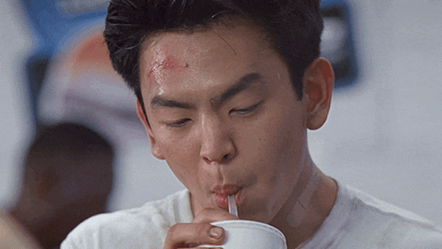 a man drinking through a straw from a cup