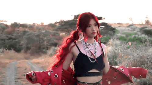 a woman with red hair is wearing a red jacket and a black top