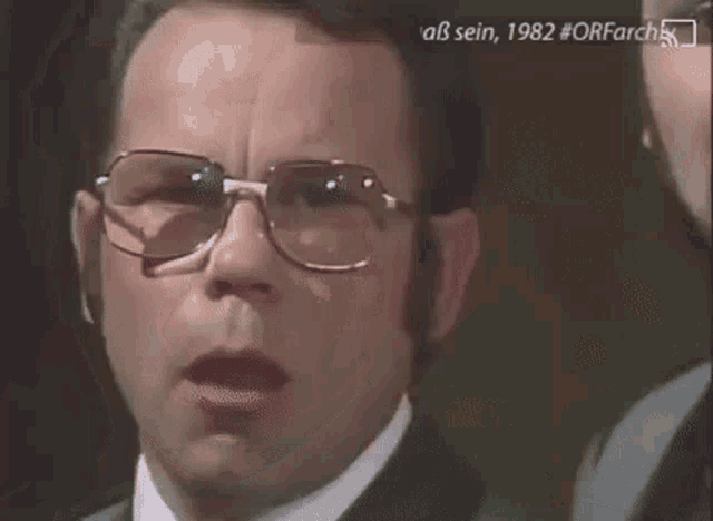 a man wearing glasses is making a surprised face .