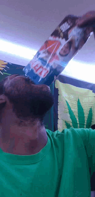 a man in a green shirt is drinking from a bag of iced tea
