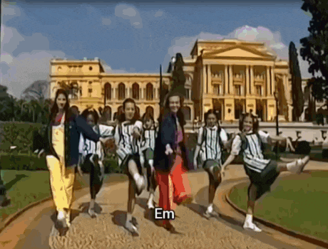 a group of people are dancing in front of a building and the word em is on the bottom
