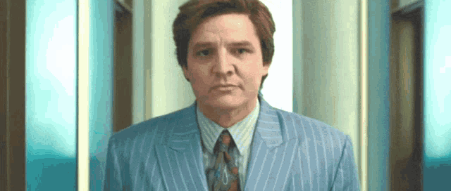 a man in a blue striped suit and tie looks at the camera