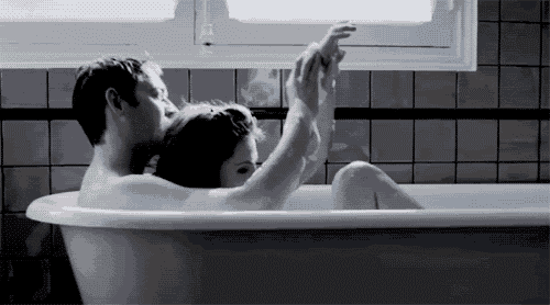 a man and a woman are taking a bath together in a bathtub .