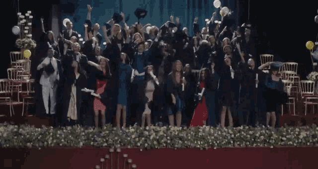 a large group of graduates are throwing their caps in the air