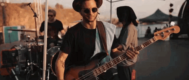 a man playing a fender bass guitar in front of a drum set