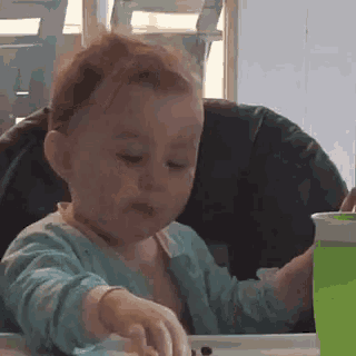 a baby is sitting in a high chair playing with a toy .