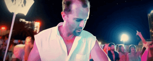 a man in a white shirt stands in front of a crowd at a party