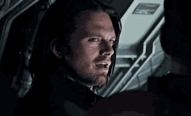 a man with long hair and a beard is looking at another man .