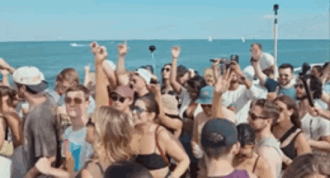 a large group of people are dancing on the beach at a party .
