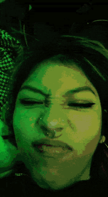 a close up of a woman 's face with a green background