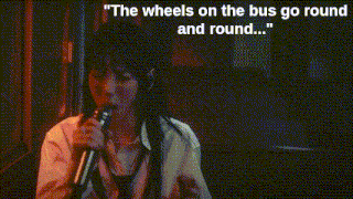 a woman singing into a microphone with the words " the wheels on the bus go round and round "