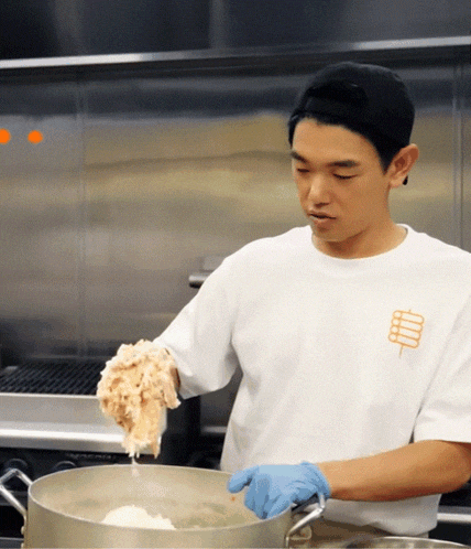 a man wearing a white shirt with a stick on it is cooking
