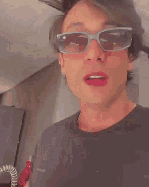 a man wearing sunglasses and a black shirt holds a glass