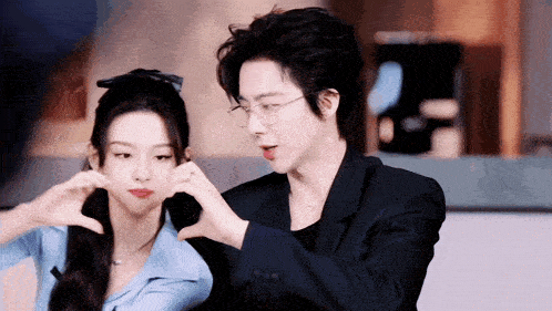 a man and a woman making a heart shape with their hands