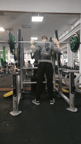 a man squatting in front of a mirror in a gym that says ' aoly ' on it