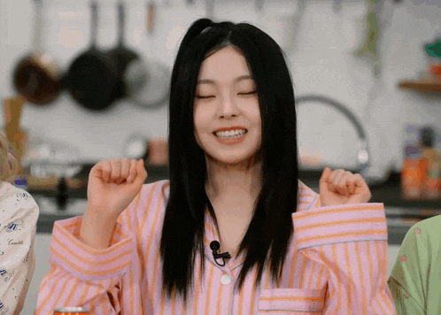 a woman wearing a pink and orange striped pajama shirt is smiling