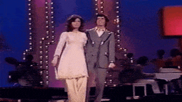 a man and a woman are standing next to each other on a stage holding hands .