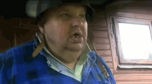 a man wearing a helmet and a blue jacket is making a face