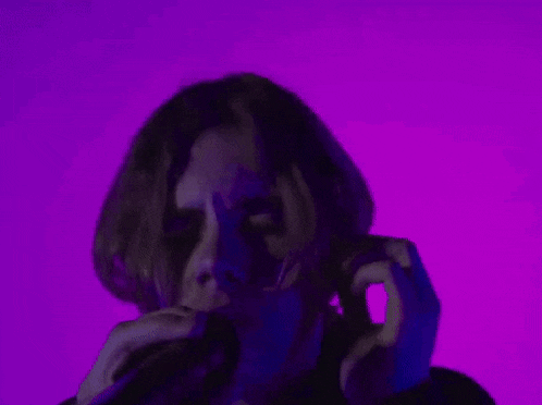 a man is talking on a cell phone in a dark room with purple lights .