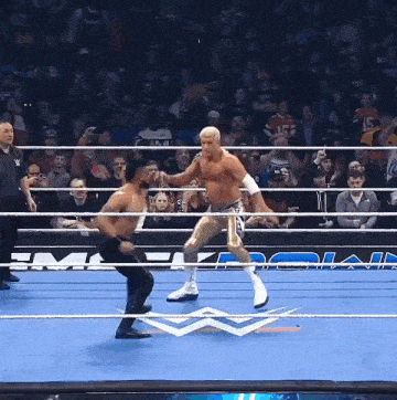 two men are wrestling in a wrestling ring with a crowd in the stands watching