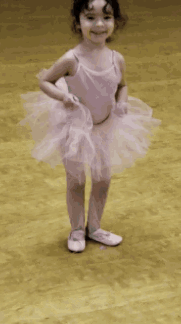a little girl is wearing a pink tutu and white shoes