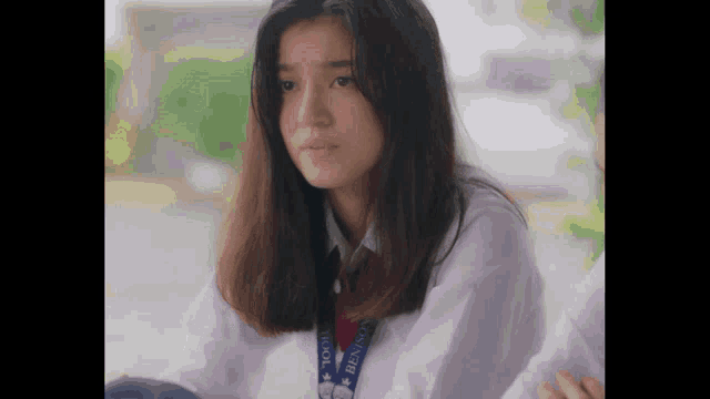 a girl wearing a white shirt and a lanyard that says ' school ' on it