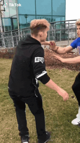 a man in a black hoodie with the word rub on the sleeve is standing in the grass