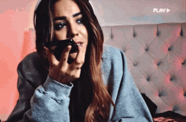 a woman talking on a phone with a play button in the corner