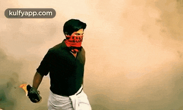 a man with a bandana on his face is holding a molotov cocktail .