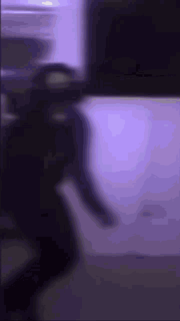 a blurry picture of a person standing in front of a purple light .
