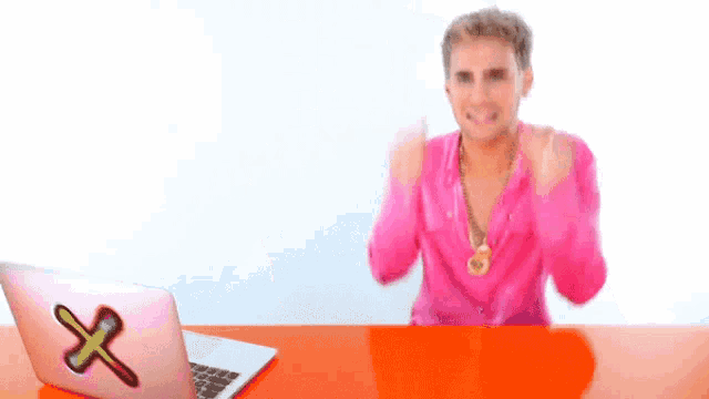 a man in a pink shirt is holding his ears .