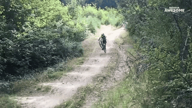 a person riding a bike down a dirt road with the words awesome written on the bottom