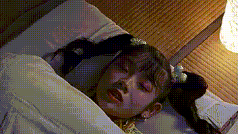 a girl with pigtails is laying in a bed with her eyes closed and her hair in pigtails .