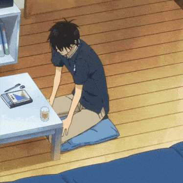 a man is sitting on a blue pillow in front of a table
