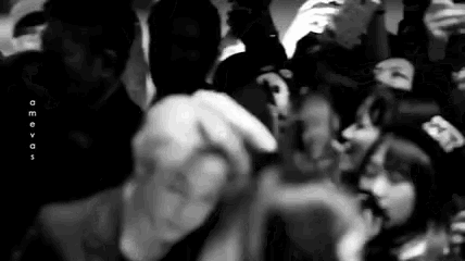 a black and white photo of a crowd of people standing around a stage .