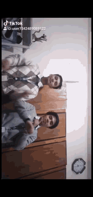 two men are standing next to each other in front of a wall with a clock on it that says tik tok