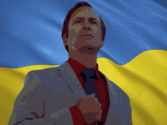 a man in a suit and tie is standing in front of a flag