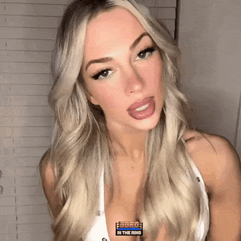 a woman with blonde hair is wearing a white tank top with a logo that says free in the ring