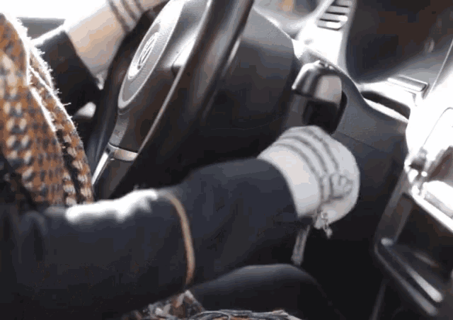 a person is driving a car with a volkswagen logo on the steering wheel