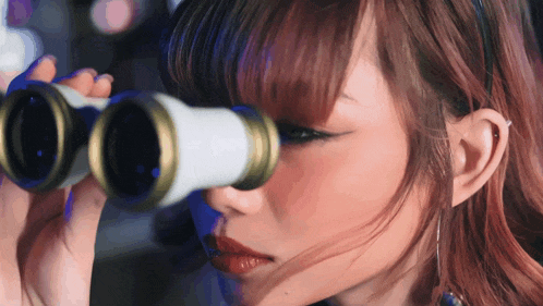 a close up of a woman looking through binoculars with red hair